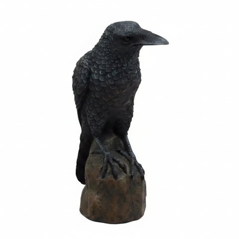 Statue of a crow perched on a branch with a white background